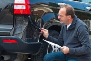 Insurance adjuster assesses damaged fender