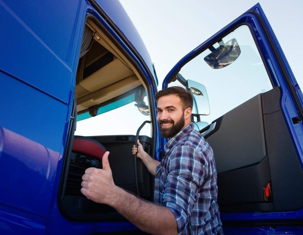 Tractor-trailer driver signals a thumbs up as he gets in cab of truck.