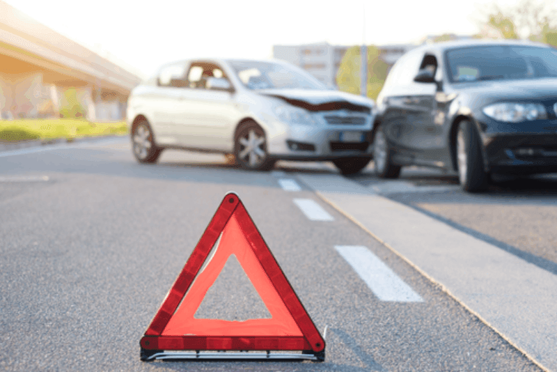 Two cars involved in a rear-end collision with a hazard triangle in the foreground.